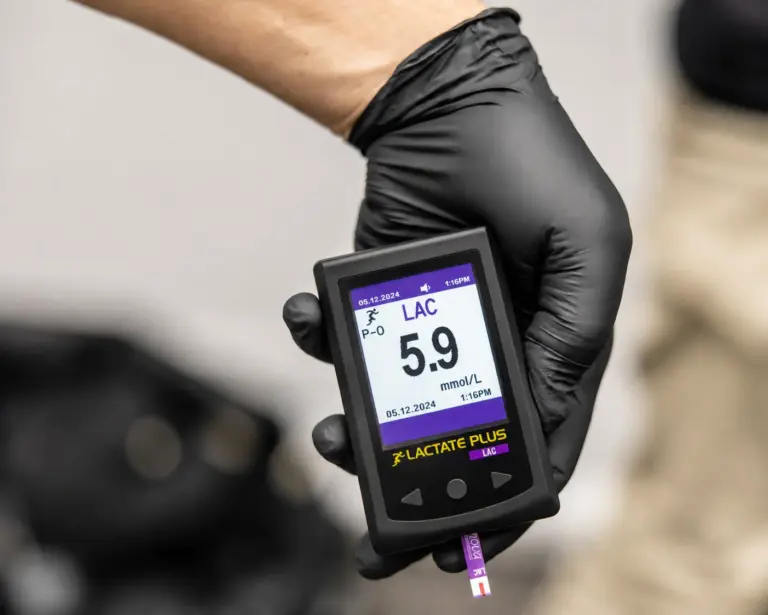 KI modifizierte Nahaufnahme eines Laktatmessgeräts mit angezeigtem Wert von 5,9 Millimol pro Liter in einer behandschuhten Hand.